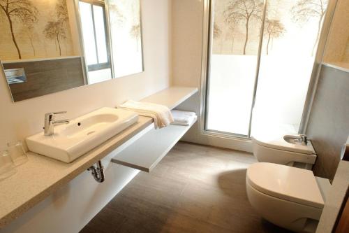 ein Badezimmer mit einem Waschbecken, einem WC und einem Spiegel in der Unterkunft Apartamentos San Francisco in Sant Antoni de Portmany