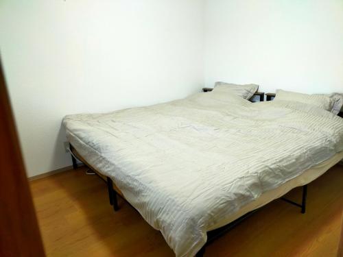a bed in a room with white sheets and pillows at 民宿 和合 Minshuku WAGO in Tanabe