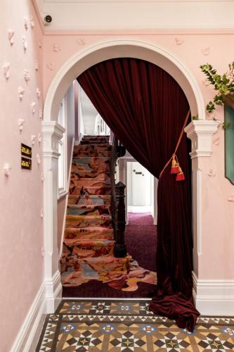 a stairway with a red curtain and a carpet at Medusa Hotel Sydney in Sydney