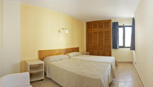 1 Schlafzimmer mit 2 Betten und einem Fenster in der Unterkunft Apartamentos San Francisco in Sant Antoni de Portmany