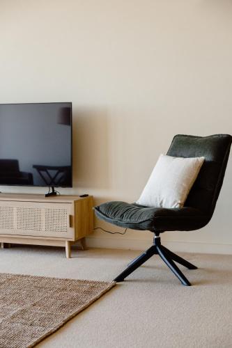 a black chair sitting in a living room with a television at Sandy Nook Beachfront Bliss with uninterrupted Ocean Views in Port Fairy