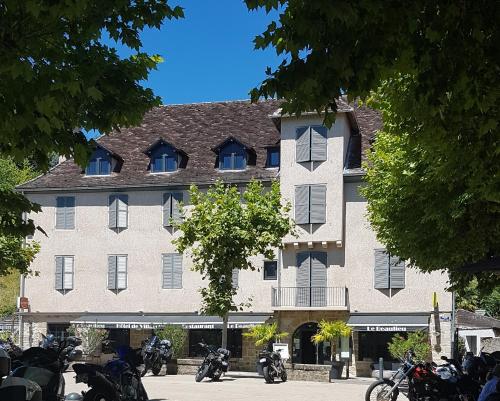 a large building with motorcycles parked in front of it at Logis Hôtel Le Beaulieu in Beaulieu-sur-Dordogne