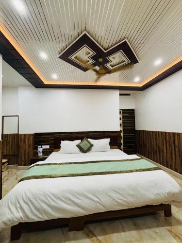 a bedroom with a large bed with a ceiling at S R Hotel in Varanasi