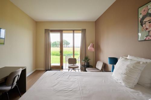 a bedroom with a large white bed and a window at Boutique Hotel het Witte Veen in Witteveen