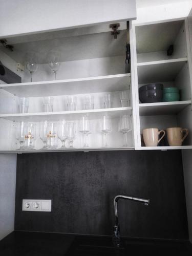 a kitchen with glasses on shelves above a sink at Ferienwohnung Maria - Bitburg in Stahl