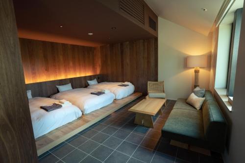 a hotel room with two beds and a bench at Nature Base Hotel NUPPUKOTTE in Teshikaga