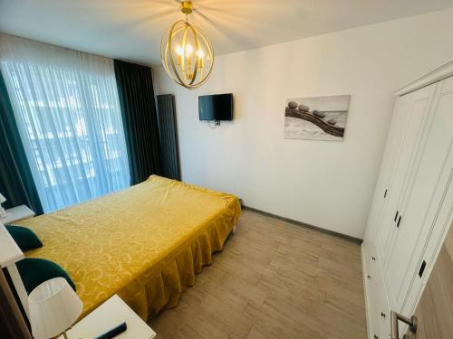 a bedroom with a yellow bed and a chandelier at Sim Seaside C1 in Mamaia Nord