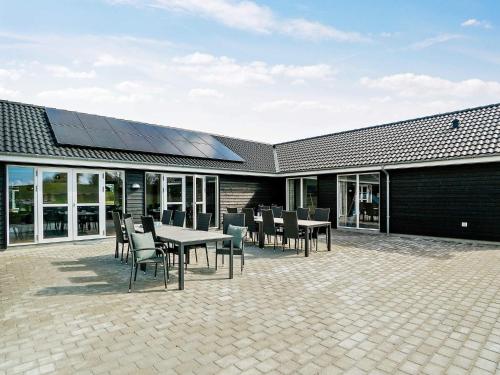 a patio with tables and chairs with a solar roof at 26 person holiday home in Grenaa in Grenå