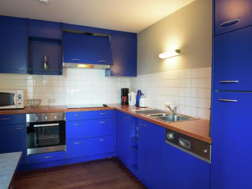 a kitchen with blue cabinets and a sink at Les Terrasses Charming cottage in the heart of the Ardennes in Waimes