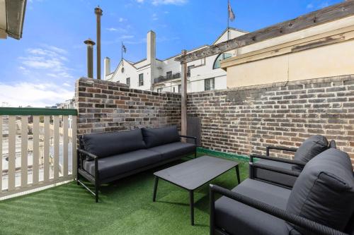 a patio with two couches and a table and a brick wall at Stunning Terraced Apartment near the Sydney Opera House in Sydney