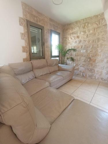 Una sala de estar con un sofá y una pared de piedra. en עלמא אירוח בגליל לציבור הדתי, en Bar Yohai
