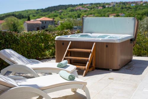 a hot tub sitting on a patio with chairs at Villa Luca with pool and jacuzzi in Vrh