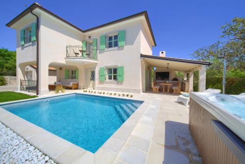 a villa with a swimming pool in front of a house at Villa Luca with pool and jacuzzi in Vrh