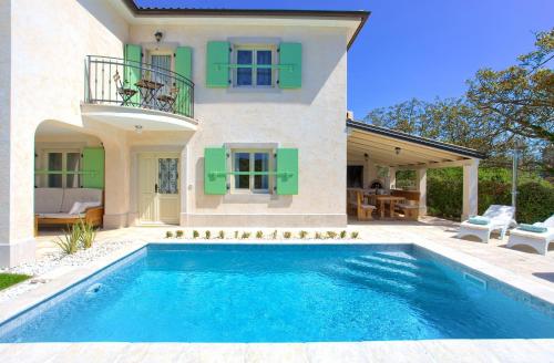 a villa with a swimming pool in front of a house at Villa Luca with pool and jacuzzi in Vrh