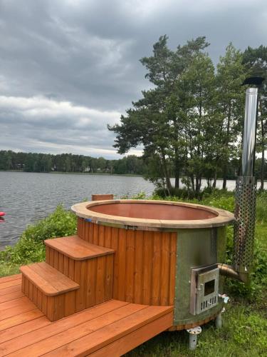 a hot tub on a deck next to a lake at Summer house Sunny coast in Lankstiņi
