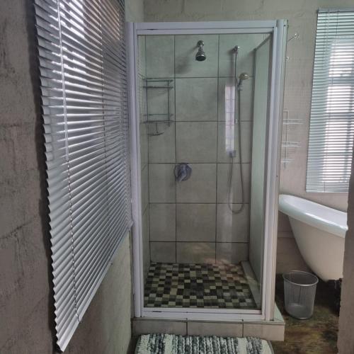 a shower with a glass door in a bathroom at Onse Boshuis in Marloth Park