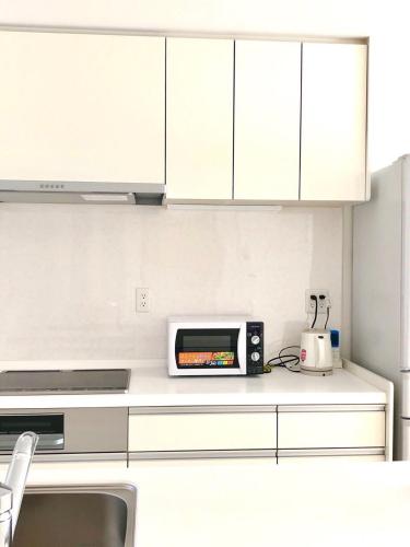 a white kitchen with a microwave on a counter at Putao in Osaka