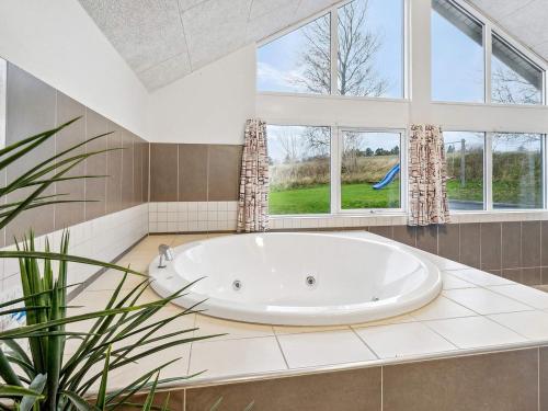 a large white tub in a bathroom with windows at Luxury Pool Retreat - By Traum Ferienwohnungen in Vejby