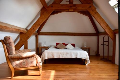 a bedroom with a bed and a chair in a attic at Maison de charme à la campagne in Dégagnac
