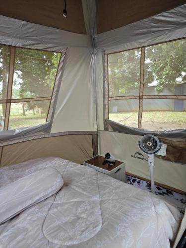 a bedroom with a bed in a tent with windows at Warisan Homestay Kampung Chinchin in Jasin