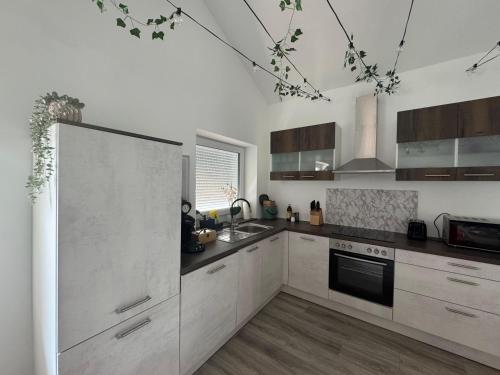 a kitchen with white cabinets and a stove top oven at Waldzauber - Moderne Ferienwohnung im Grünen in Elpenrod