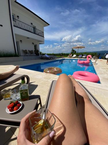 a woman laying on a chair with a glass of wine next to a pool at Vila sa bazenom Vrnjačka Idila in Vrnjačka Banja