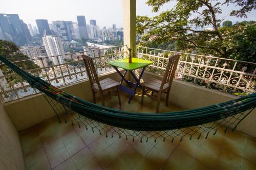 eine Hängematte auf einem Balkon mit einem Tisch und 2 Stühlen in der Unterkunft Rio Forest Hostel in Rio de Janeiro