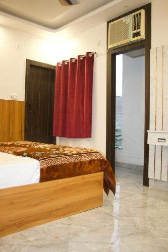 a bedroom with a bed with red curtains and a window at The Golden Inn in Lucknow