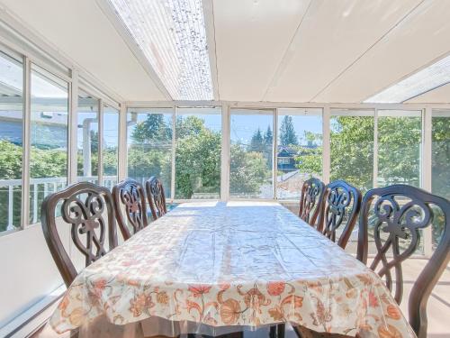 a dining room with a table and chairs and windows at Cozy Airb&b Suite in South Vancouver in Vancouver