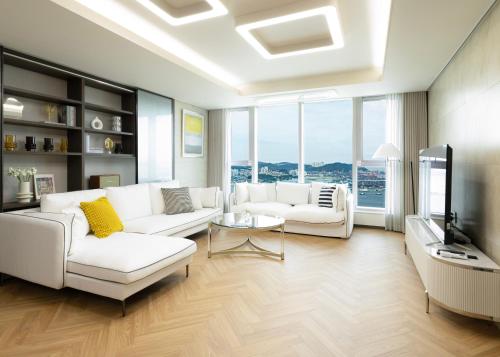 a living room with white couches and a television at Brown Suites Busan Station in Busan
