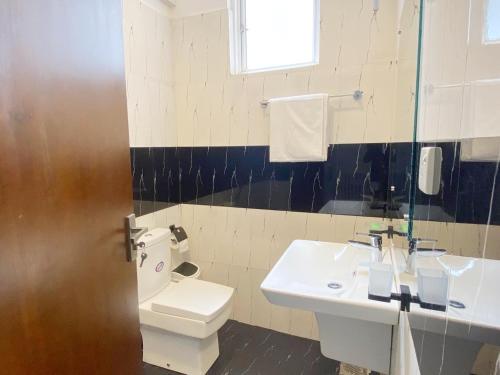 a bathroom with a white toilet and a sink at Marine Blue Apartment in Dehiwala