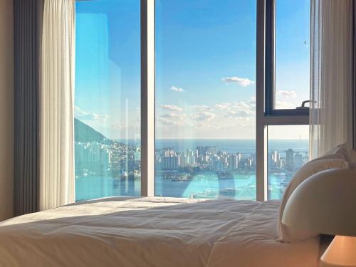 a bedroom with a large window with a view of a city at Brown Suites Busan Station in Busan