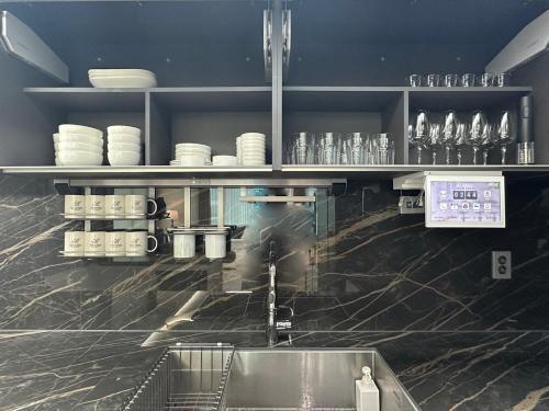 a kitchen with a sink and shelves with dishes at Brown Suites Busan Station in Busan