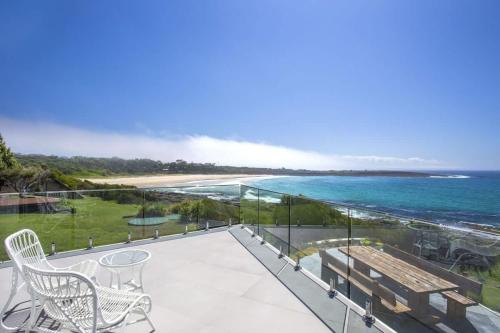 a balcony with chairs and a view of the ocean at Bawley Point Beach Front - oceanfront luxury home in Bawley Point
