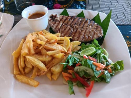a plate of food with a steak and french fries at Zanzibar Dream Lodge in Bwejuu
