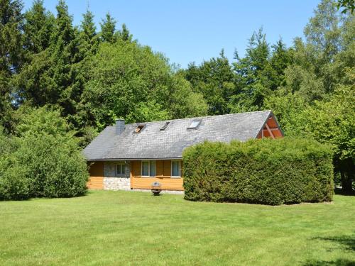 a house in the middle of a yard with trees at Comfortable Chalet in Ovifat near Ski Lift in Waimes