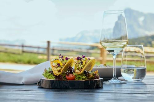 a plate of food and a glass of wine on a table at COMO Alpina Dolomites in Alpe di Siusi