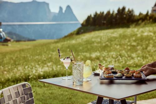a table with a plate of food and a drink at COMO Alpina Dolomites in Alpe di Siusi
