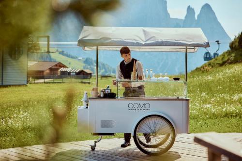 a man is standing behind a food cart at COMO Alpina Dolomites in Alpe di Siusi