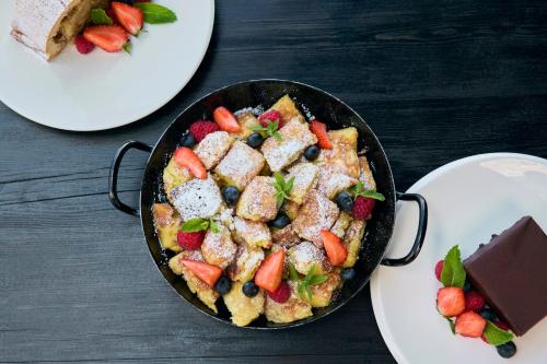 a pan of food on a table next to plates of food at COMO Alpina Dolomites in Alpe di Siusi