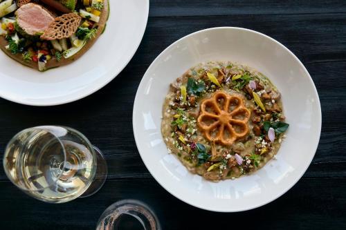 a table with two plates of food and a glass of wine at COMO Alpina Dolomites in Alpe di Siusi