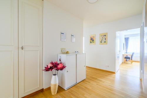 a white room with a vase with flowers in it at Apartment Arnold in Basel