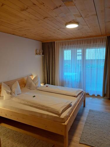 a large bed in a room with a large window at Haus Vögel in Sibratsgfäll