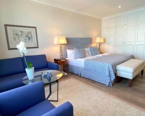 a bedroom with a bed and two blue couches at Grand Hotel Seeschlösschen Sea Retreat & SPA in Timmendorfer Strand
