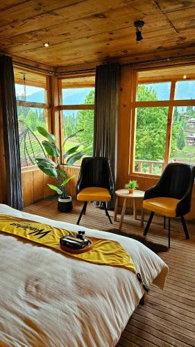 a bedroom with a bed and two chairs and windows at Wanderlust Chapter 2 in Arangkēl