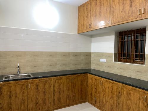 a kitchen with wooden cabinets and a sink at Shivalaya Rooms in Tiruvannāmalai