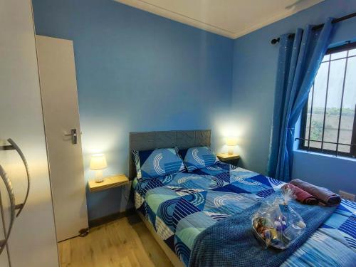 una camera da letto con un letto con pareti blu e una finestra di Swallows Rest Cottage KZN a Scottburgh
