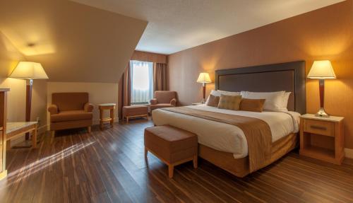 a hotel room with a large bed and two chairs at Coast Hillcrest Hotel in Revelstoke