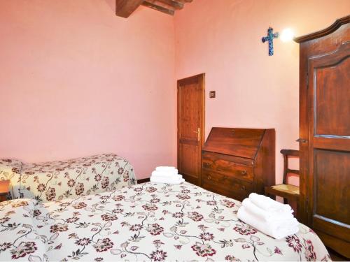 a bedroom with a bed and a dresser and a cross on the wall at Rustic Holiday Home in Città di Castello with Swimming Pool in Città di Castello
