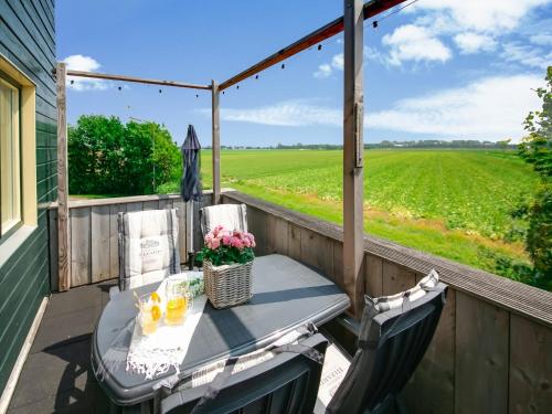 a table and chairs on a porch with a view of a field at Beautiful Apartment in Callantsoog near Beach in Callantsoog
